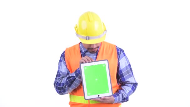 Счастливый бородатый персидский рабочий строитель думает, показывая цифровой планшет — стоковое видео