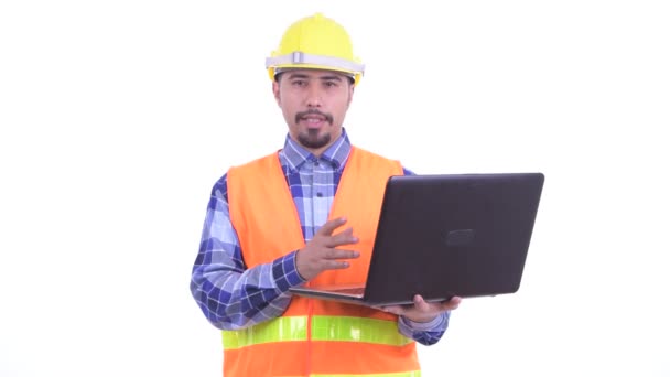 Счастливый бородатый перс строитель говорит во время использования ноутбука — стоковое видео