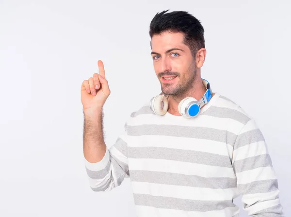 Retrato de homem barbudo bonito feliz com fones de ouvido apontando para cima — Fotografia de Stock