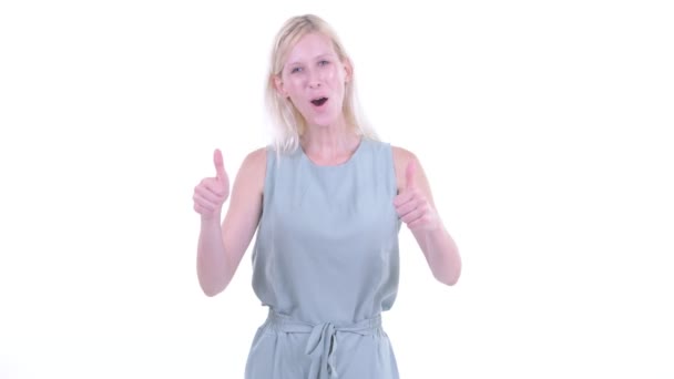 Glücklich junge schöne blonde Frau gibt die Daumen nach oben und sieht aufgeregt — Stockvideo