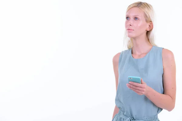 Portret młodej pięknej blond kobieta myślenia podczas korzystania z telefonu — Zdjęcie stockowe