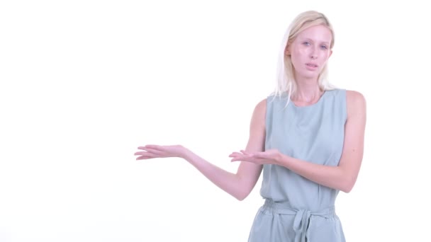 Benadrukte jonge blonde vrouw die iets toont — Stockvideo