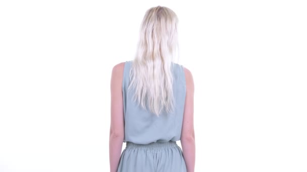 Вид сзади на молодую блондинку, думающую и оглядывающуюся — стоковое видео