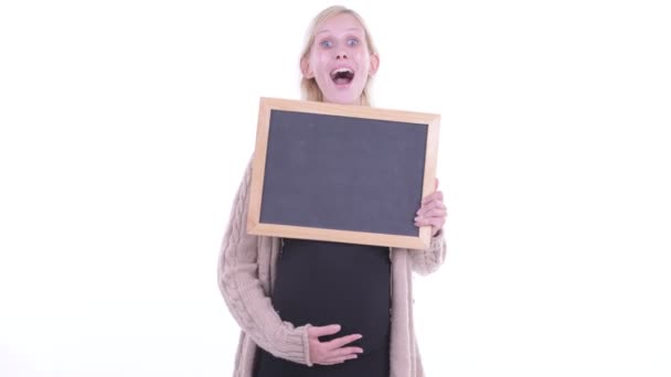 Happy young blonde pregnant woman holding blackboard and getting good news — Stock Video