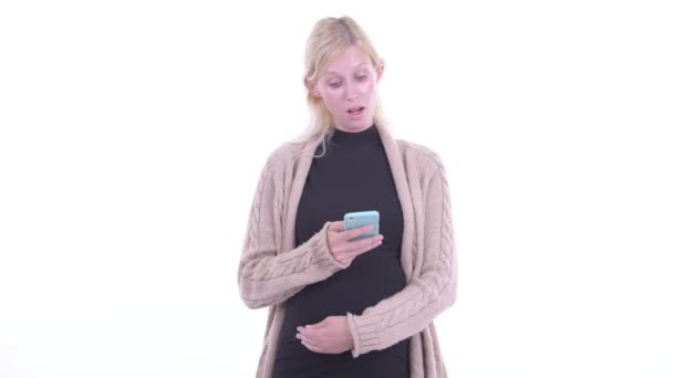 Ευτυχισμένος νεαρή ξανθιά έγκυος γυναίκα σκέφτεται ενώ χρησιμοποιεί το τηλέφωνο — Αρχείο Βίντεο