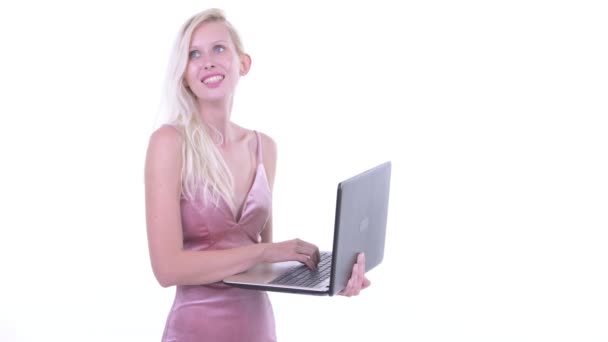 Happy young beautiful blonde woman thinking while using laptop — Stock Video