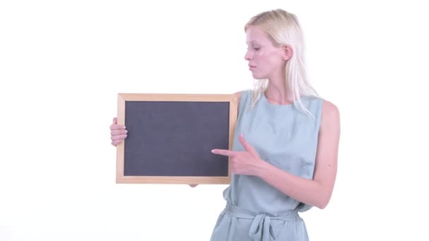 Stressed young blonde woman holding blackboard and giving thumbs down — Stock Video