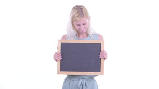 Mujer rubia joven estresada sosteniendo pizarra y recibiendo malas noticias — Vídeo de stock