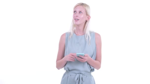 Lycklig ung vacker blond kvinna tänkande när du använder telefonen — Stockvideo