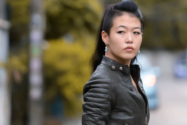 Porträt der schönen asiatischen rebellischen Frau, die im Freien über die Schulter schaut — Stockfoto