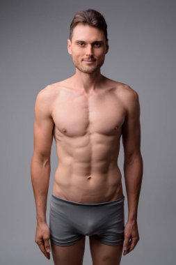Gri arka plan karşı yakışıklı kaslı adam gömleksiz Stüdyo çekim