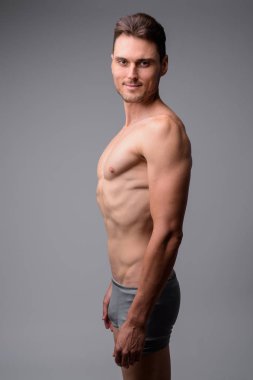 Gri arka plan karşı yakışıklı kaslı adam gömleksiz Stüdyo çekim