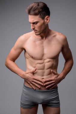 Gri arka plan karşı yakışıklı kaslı adam gömleksiz Stüdyo çekim