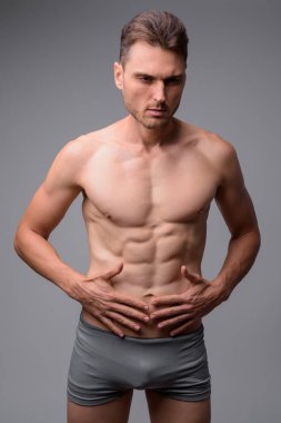 Gri arka plan karşı yakışıklı kaslı adam gömleksiz Stüdyo çekim