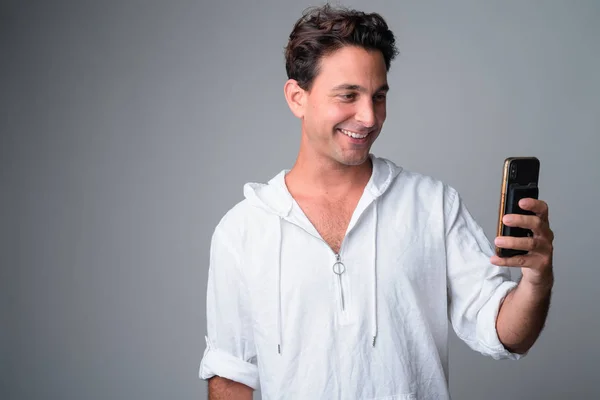Retrato de homem hispânico bonito feliz sorrindo e usando telefone — Fotografia de Stock