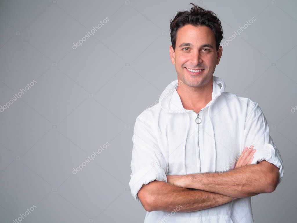 Portrait of happy handsome Hispanic man smiling with arms crossed