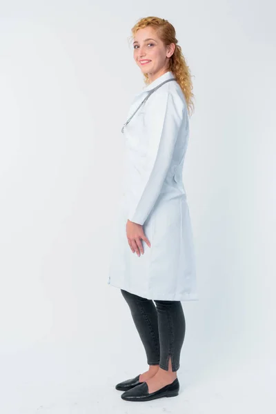 Full body shot profile view of happy blonde woman doctor looking at camera Stock Photo