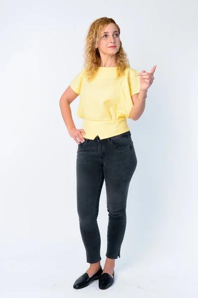 Full body shot of beautiful woman with curly blond hair pointing finger — Stock Photo, Image