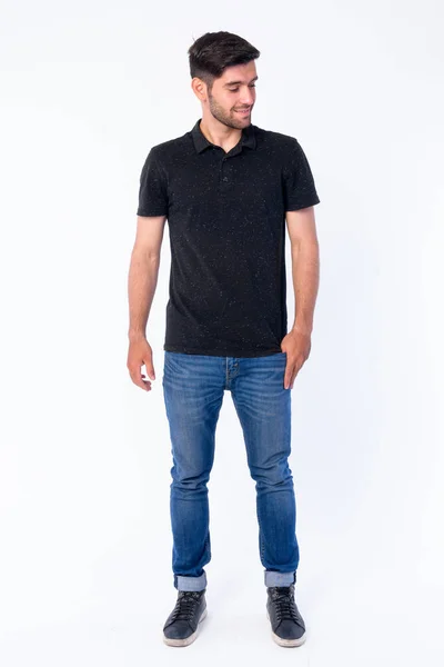 Full body shot of happy young bearded Persian man thinking and looking down — Stock Photo, Image