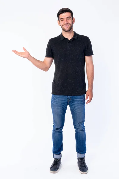 Full body shot of happy young bearded Persian man showing something — Stock Photo, Image