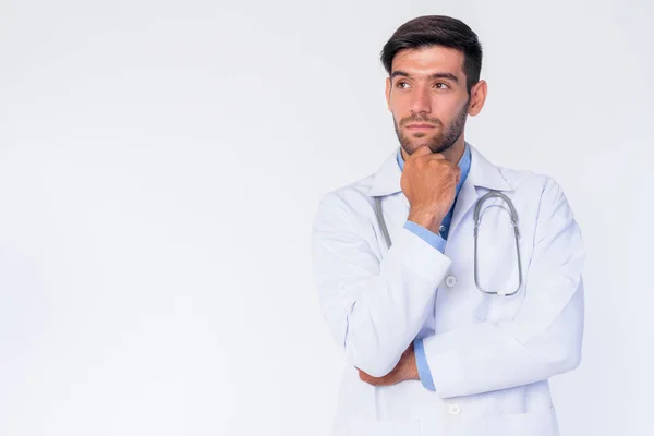 Portrait of young bearded Persian man doctor thinking and looking up — Stok Foto