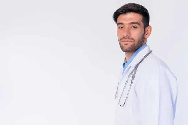 Profil kilátás fiatal szakállas perzsa férfi orvos nézi kamera — Stock Fotó