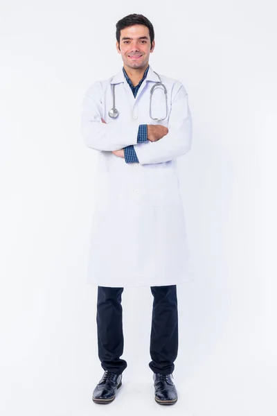 Full body shot of happy young Persian man doctor smiling with arms crossed — Stock Photo, Image