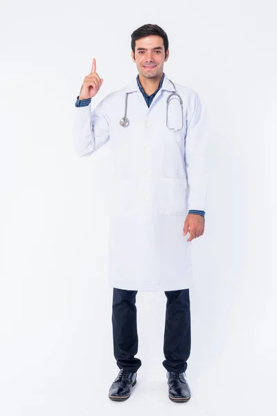 Full body shot of happy young Persian man doctor pointing up — Stock Photo, Image