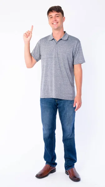 Full body shot of happy young handsome man pointing up — Stock Photo, Image