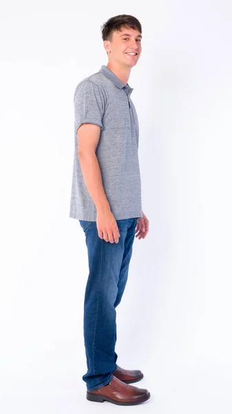 Full body shot profile view of happy young handsome man looking at camera — Stock Photo, Image