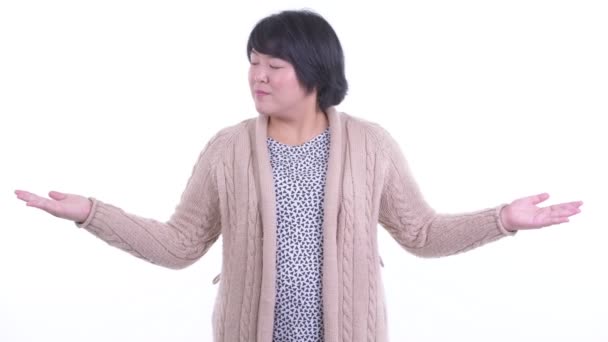 Glad överviktig asiatisk kvinna jämför något redo för vintern — Stockvideo