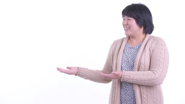 Heureuse femme asiatique en surpoids montrant quelque chose pour l'hiver — Video