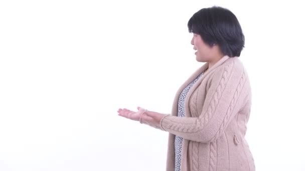 Glad överviktig asiatisk kvinna visar på baksidan för vintern — Stockvideo