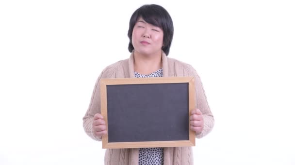 Feliz sobrepeso mujer asiática pensando mientras sostiene pizarra listo para el invierno — Vídeos de Stock