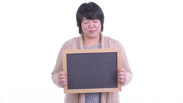 Έκπληκτος υπέρβαρη ασιατική γυναίκα κρατώντας μαυροπίνακα έτοιμο για το χειμώνα — Αρχείο Βίντεο