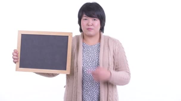 Счастливая толстая азиатка держит доску и подает большие пальцы на зиму — стоковое видео