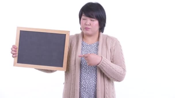 Напряженная азиатка с избыточным весом держит доску и подает большие пальцы на зиму — стоковое видео