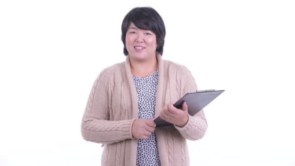 Felice donna asiatica in sovrappeso intervistando con appunti pronti per l'inverno — Video Stock