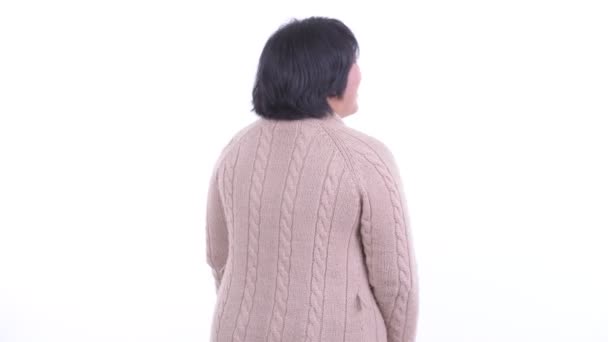 Vista trasera de la mujer asiática feliz con sobrepeso pensando y mirando alrededor en invierno — Vídeo de stock