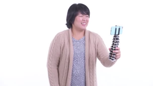 Glad överviktig asiatisk kvinna vloggar med telefon redo för vintern — Stockvideo