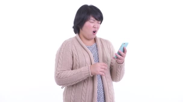 Stressad överviktig asiatisk kvinna med telefon och få dåliga nyheter för vintern — Stockvideo
