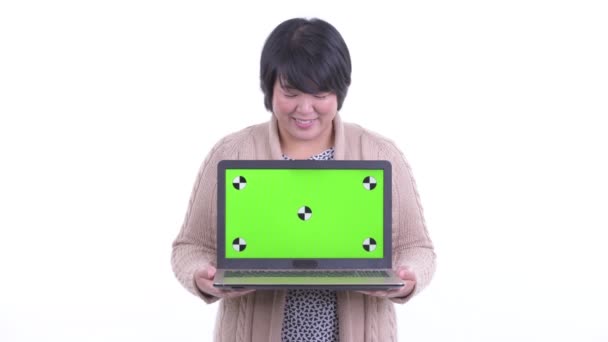 Glad överviktig asiatisk kvinna tänker medan du visar laptop redo för vintern — Stockvideo