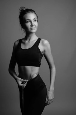 Gri arka planda jimnastiğe hazır güzel bir kadının stüdyo çekimi.