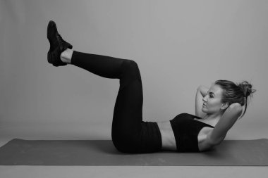 Gri arka planda jimnastiğe hazır güzel bir kadının stüdyo çekimi.