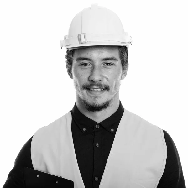 Közelkép a boldog fiatalember építőmunkás mosolyogva, miközben vágólap elszigetelt fehér háttér — Stock Fotó