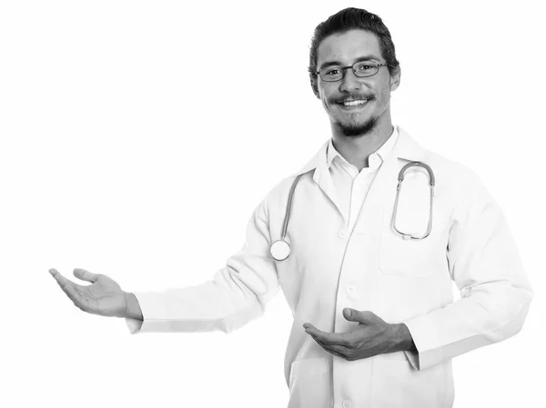 Студійний знімок молодого щасливого лікаря, який посміхається, показуючи щось ізольоване на білому тлі — стокове фото