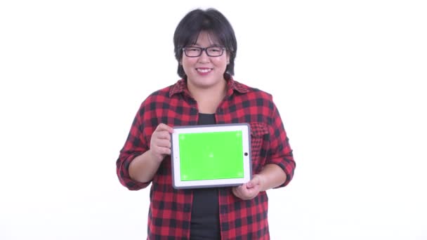 Glücklich übergewichtige asiatische Hipster-Frau denken, während sie digitales Tablet zeigt — Stockvideo