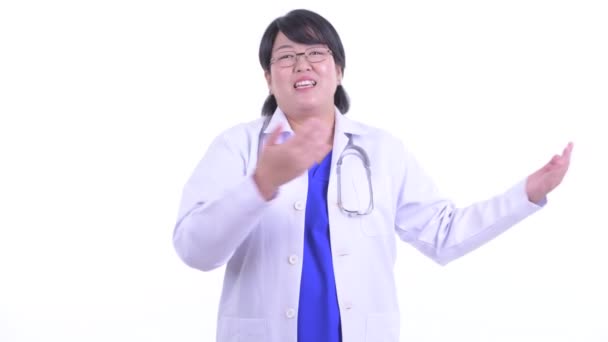 Χαρούμενος υπέρβαρων Ασιάτης/ισσα γυναίκα γιατρός παρουσιάζοντας κάτι — Αρχείο Βίντεο
