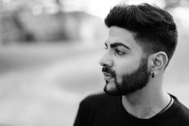 Genç yakışıklı Hintli adam parkta düşünme profili görünümünü kapat