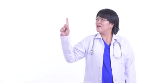 Happy overweight Asian woman doctor talking while pointing up — Stock Video